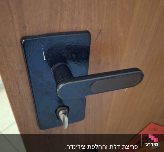 ידית דלת מתכתית על דלת עץ